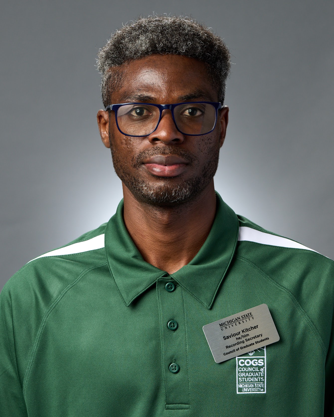 Savior Kitcher wearing a green MSU shirt against a grey background.