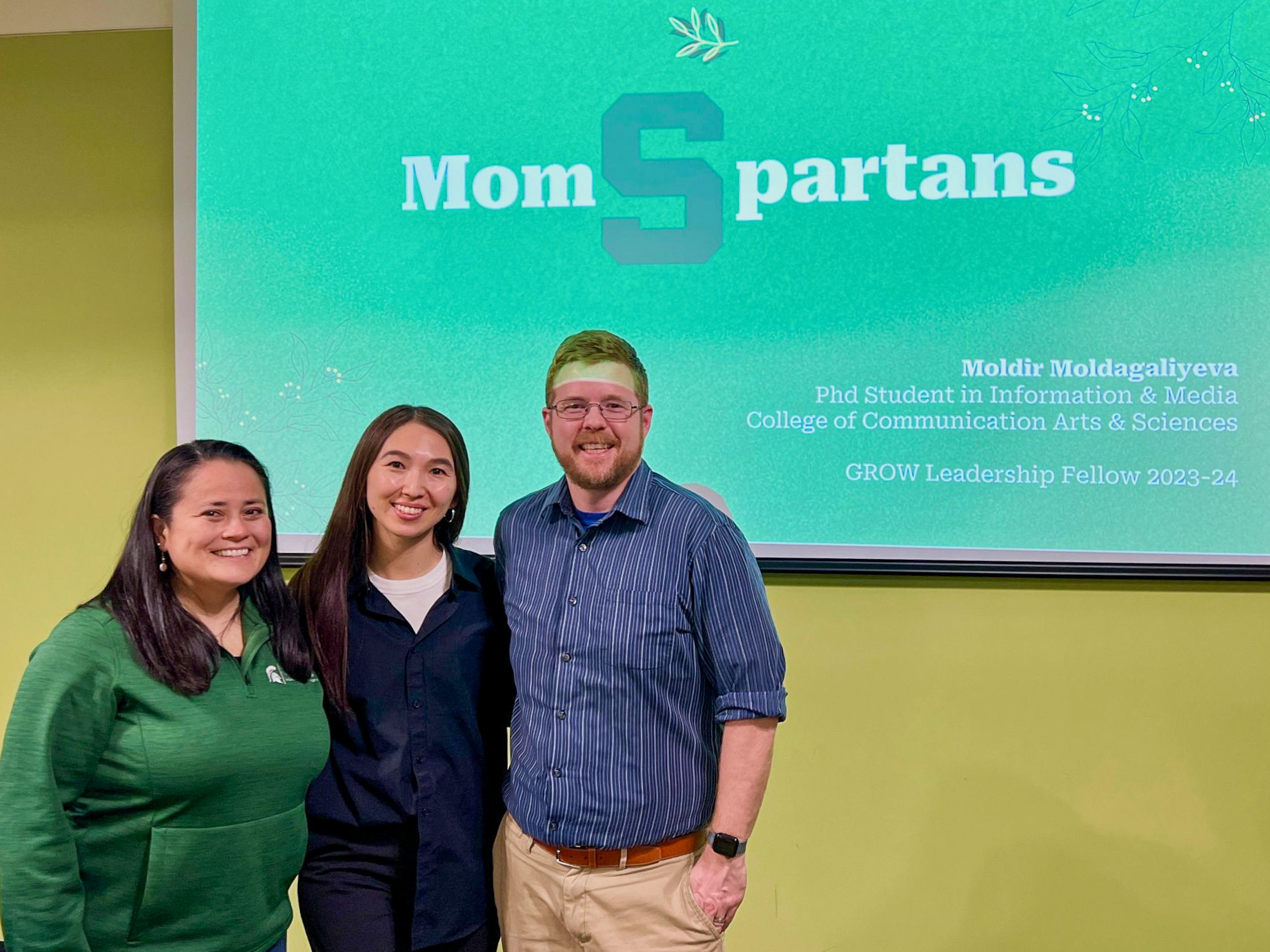 Leadership Fellow Moldir Moldagaliyeva presenting MOMSpartans Leadership Fellow Moldir Moldagaliyeva in front of a screen displaying the word "MomSpartans"