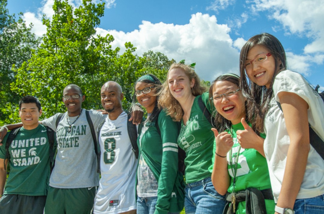 a group of smiling MSU students posing for a photo outdoors.