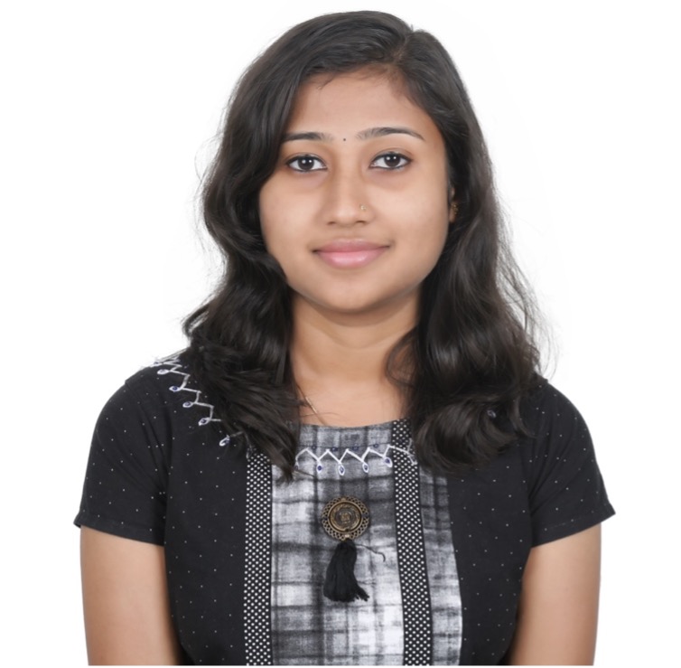 Devika standing in a black shirt in front of a white backdrop.