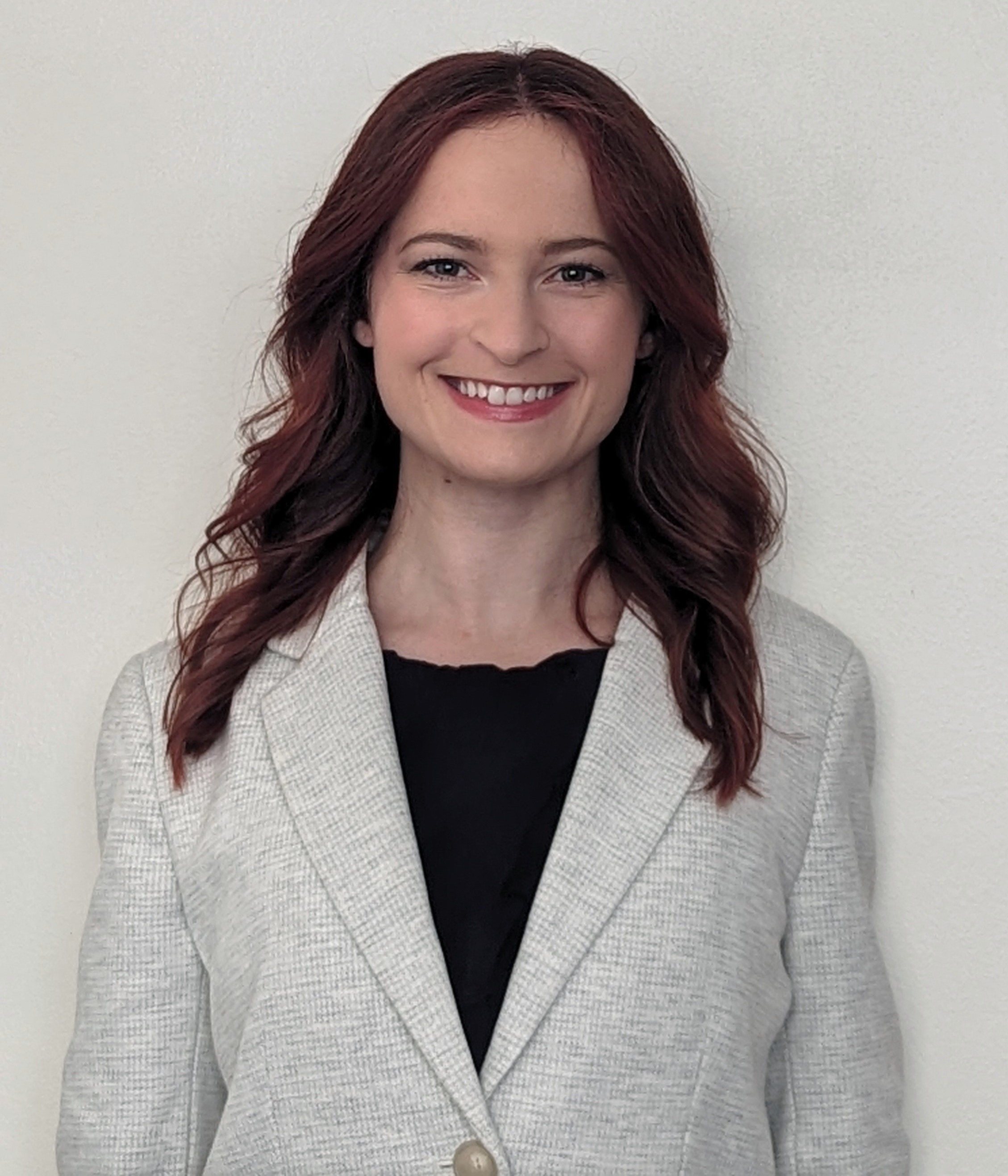 Maura wearing a white suit coat.