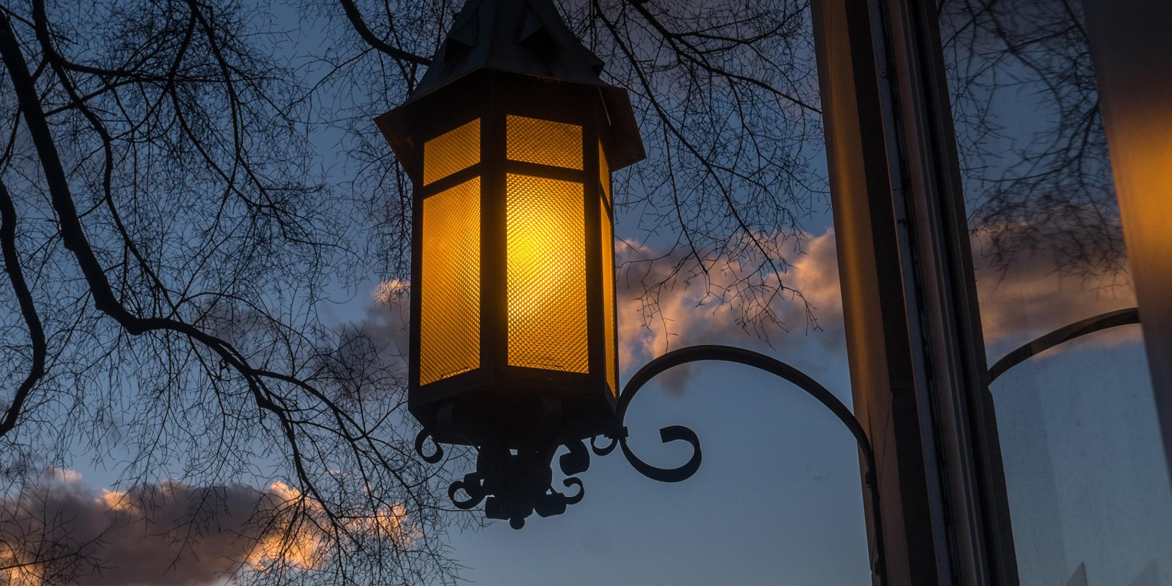 An illuminated lantern, silhouetted by an evening sky. 