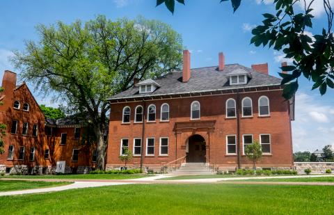 A large red brick building on a summer day with blue skies