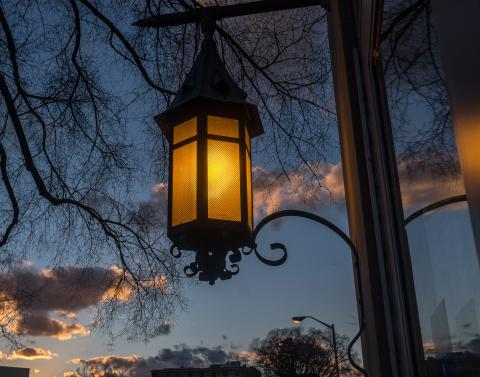 An illuminated lantern, silhouetted by an evening sky. 