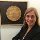 Devon Brenner standing in front of the seal of the State of Mississippi